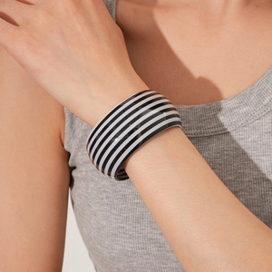Close-up of minimalist black and white striped wide cuff bracelet worn on the wrist