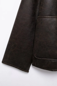 Detail shot of vintage dark brown faux leather jacket sleeve and large pocket texture