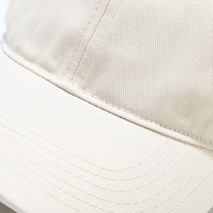 Macro shot of beige cotton twill fabric and reinforced stitching on a baseball cap