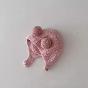 Pink knit baby beanie with plush pom-poms and ear flaps for winter warmth