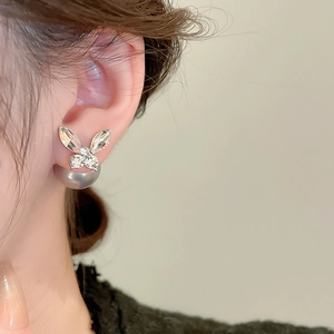 Close-up of elegant bow-shaped diamond earrings with pearl backing worn on a model's ear