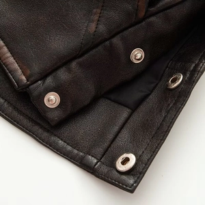 Detailed macro shot of dark brown faux leather jacket texture with silver snap buttons