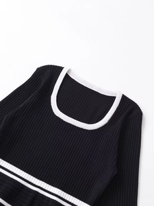 Close-up of black ribbed knit top with white contrast edging and cutout details