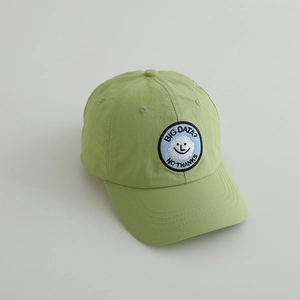Nahaufnahme einer hellgrünen Kinderkappe mit Smiley-Stickerei und Text auf der Vorderseite