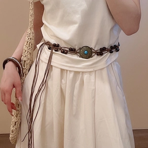 Detail of ethnic waist belt with dark brown woven rope and turquoise metal disk