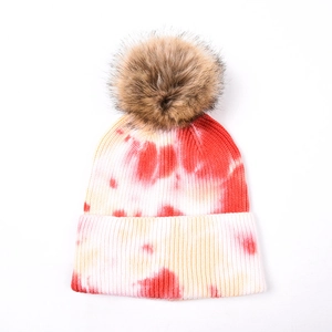 Détail d'un bonnet en tricot tie-dye avec pompon en fausse fourrure et texture douce