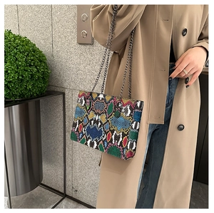 Fashionable snake print shoulder bag with grey chain strap shown on a camel trench coat