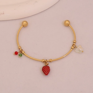 Detailed macro view of a gold-plated flower heart bracelet with a red strawberry charm