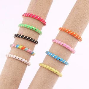 Adjustable twisted enamel gold rings in vibrant colors on a display stand