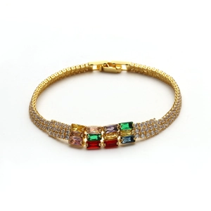 Dettaglio di bracciale dorato con cristalli rettangolari colorati e pavé di zirconi