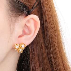 Detailed close-up of French-style shell flower earrings with golden petals and pearls