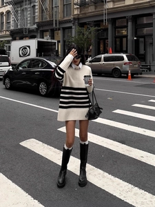 Chic street style detail of black and white striped oversized knit sweater with boots