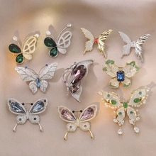 Detailed flat lay of butterfly brooches with colorful crystals and enamel on soft fabric