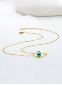 Macro detail of a gold-toned stainless steel Evil Eye pendant necklace on white background