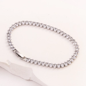 Detail eines silbernen Tennisarmbands mit Marquis-Zirkonia auf weißem Steinsockel