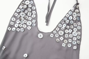 Détail de la robe grise dos nu avec des embellissements de boutons en nacre blanche