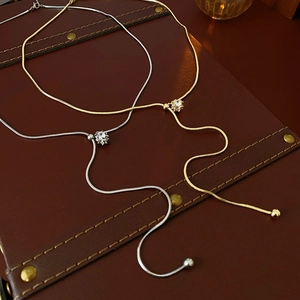Detailed macro of gold and silver snake chain necklaces with zircon pendants on leather
