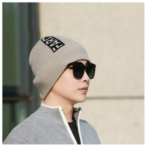 Beanie detail featuring a beige ribbed knit texture and black HARD patch on the side