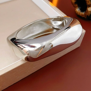 Polished silver metal cuff bracelet with an irregular wide design and a hinged closure
