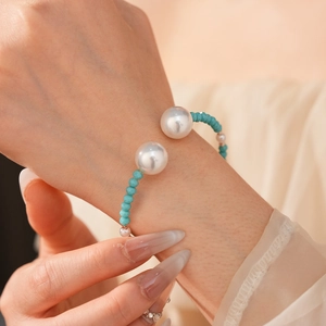 Détail d'un bracelet de perles avec pierres turquoise et grosses perles blanches