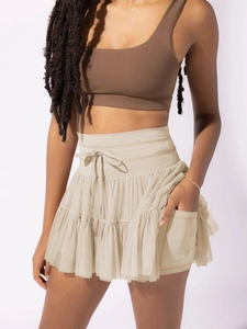 Detailed view of high waisted beige mesh skort featuring functional side pockets and drawstring