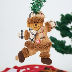 Detail of a plush Christmas bear ornament with checkered scarf on a green pine branch
