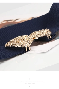 Detailed close-up of dark blue elastic belt with golden textured metal butterfly buckle