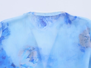 Dettaglio camicetta in chiffon blu a fiori con bordo in pizzo bianco rifinito