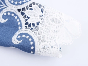 Detailaufnahme der eleganten weißen floralen Spitzenstickerei auf dunkelblauem Denim