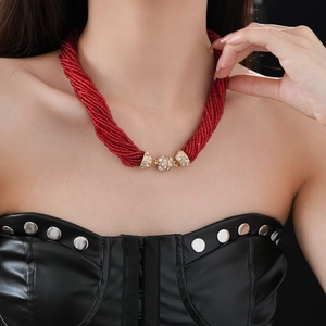 Dettaglio di collana di perle rosse multistrato con chiusura magnetica dorata su modella