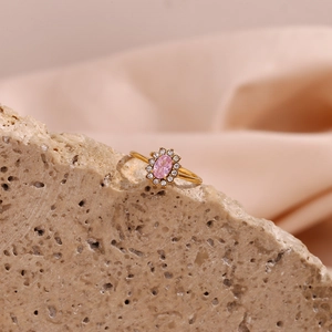 Detailed shot of an 18K gold plated oval pink zircon ring on a beige stone surface