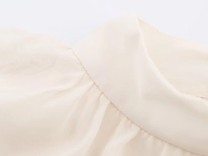 Detailed close-up of neat stitching and soft georgette fabric on a beige blouse