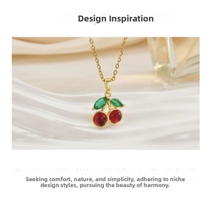 Detailed view of red zircon cherry pendant on gold chain atop a white ripple plate