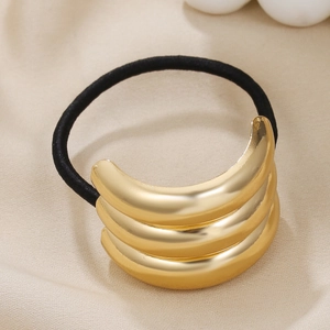 Detail of a triple-layered gold curved metal cuff on a black elastic hair tie