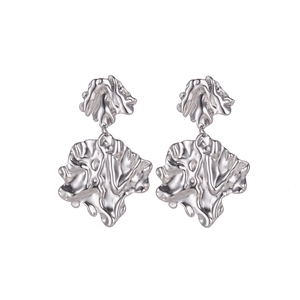 Detailed view of silver irregular leaf earrings with lava texture on white background