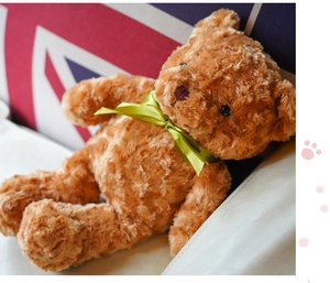 Detailed close-up of a soft brown curly fur teddy bear with a stylish green ribbon.