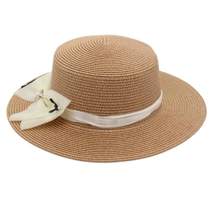 Close-up of flat top straw sun hat featuring elegant white ribbon and pearl bow detail