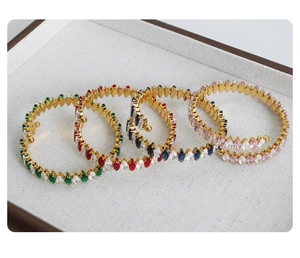Detail of four gold-plated bangles with colorful marquise-cut cubic zirconia in a jewelry tray