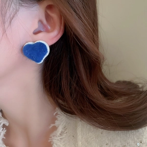 Close-up of blue flocked heart bear earrings worn on ear showing soft velvet texture