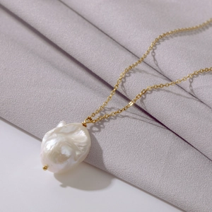 Macro detail of natural baroque pearl pendant on an elegant gold water wave chain