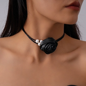 Detail view of a black silk flower choker with pearls on an elegant woman neck