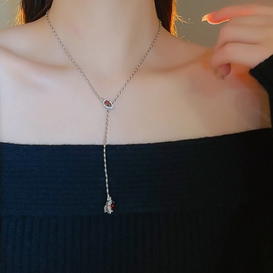 Detail of silver snake-style Y-necklace with red teardrop zircon on a model