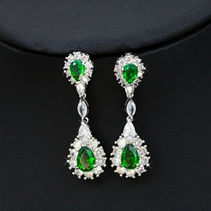 Detailed macro view of pear-cut emerald teardrop earrings with shimmering zircon halo