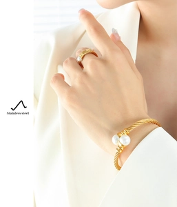 Detail of twisted gold stainless steel jewelry set featuring elegant white pearls