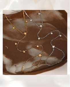 Detail of minimalist gold and silver star hand chains on a vintage ceramic display dish