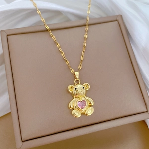 Close-up of golden bear pendant with a sparkling pink heart gemstone on silk
