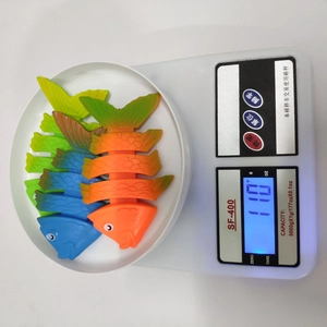 Three colorful flexible fish diving toys shown on an electronic scale for weight measurement