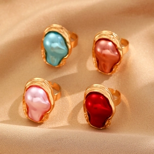 Four baroque pearl open rings in blue and pink tones set on gold textured silk background