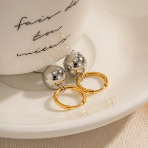 Macro detail of two-tone gold and silver ball drop earrings on white ceramic dish