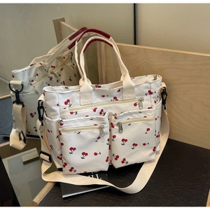 Detail view of canvas tote bag featuring cherry print, multiple pockets and long strap